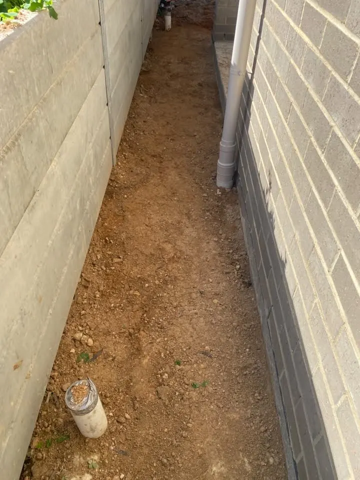 Prepped dirt along a block wall with a pipe standing up