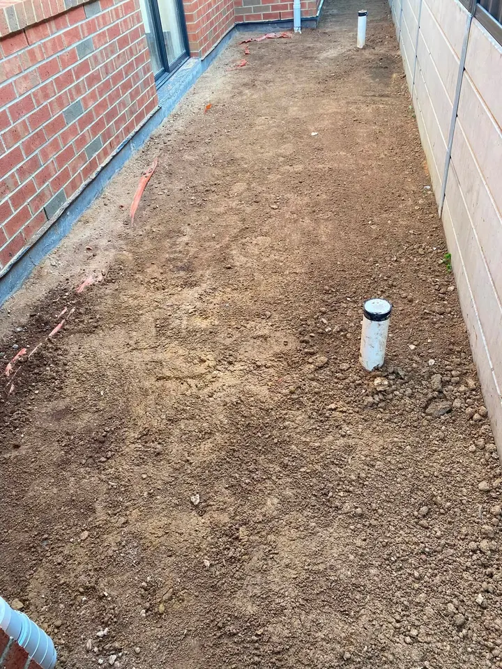 Dirt along a brick wall, a pipe standing up out of it