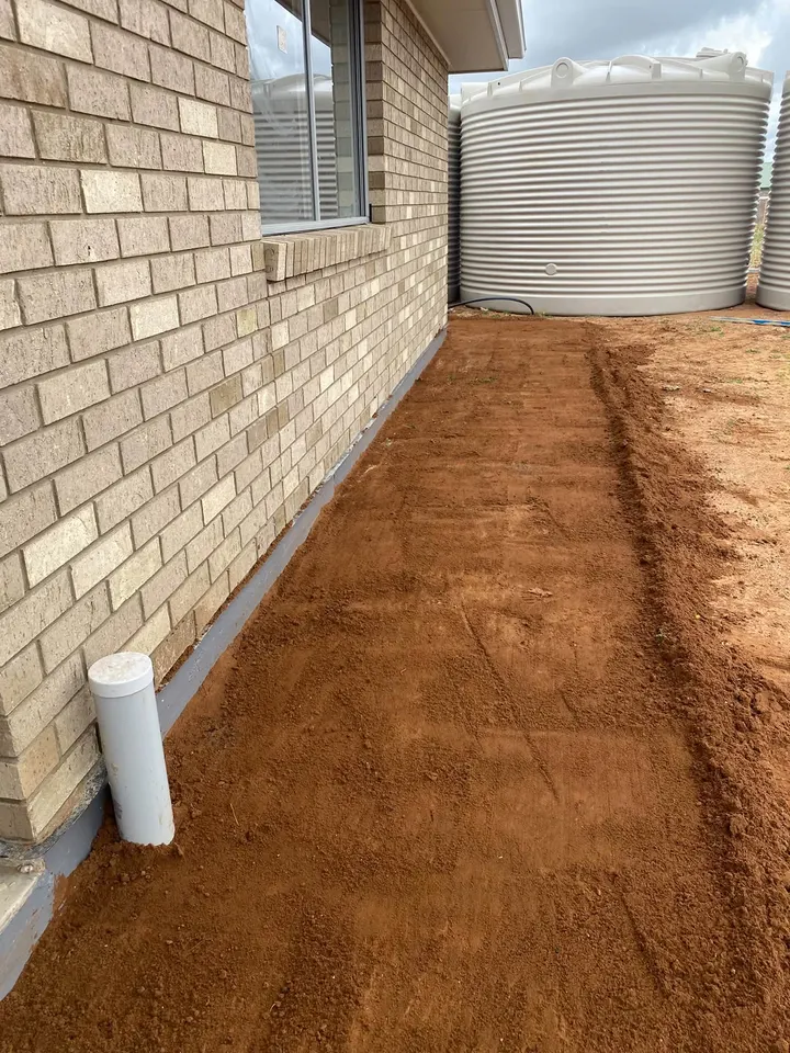 Red dirt levelled off down the side of a house